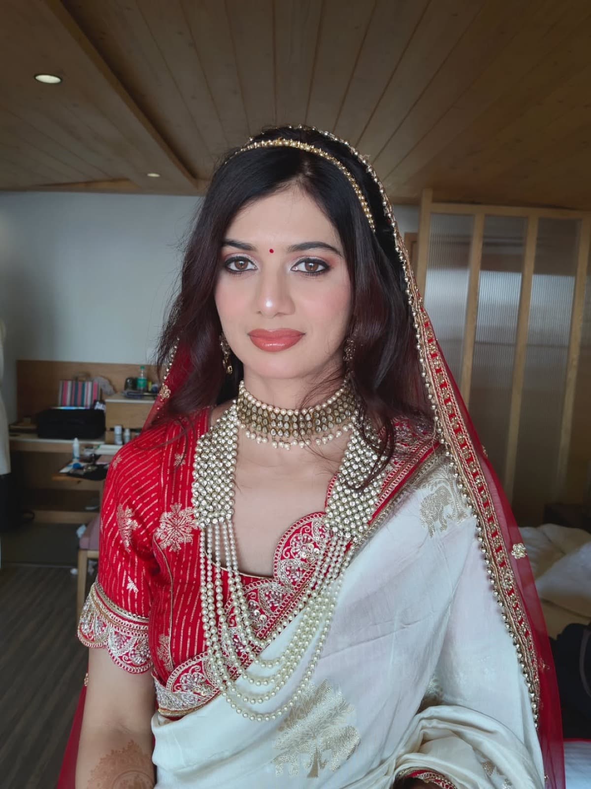 Traditional bridal makeup with terracotta lips, gold kundan choker, and red dupatta draped over head