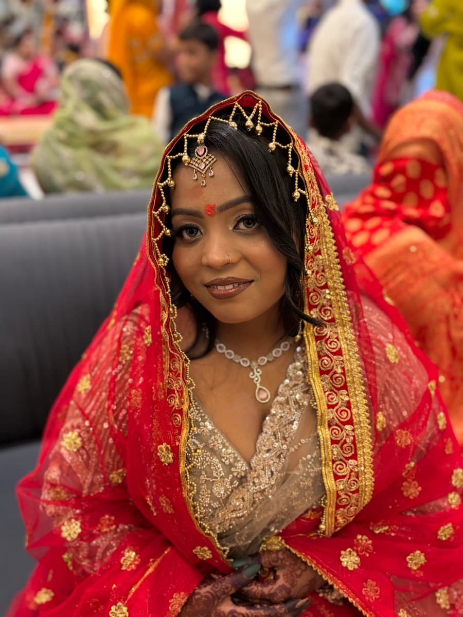 Engagement makeup with soft smokey eyes, gold maang tikka and red dupatta on a bride in a red and gold lehenga