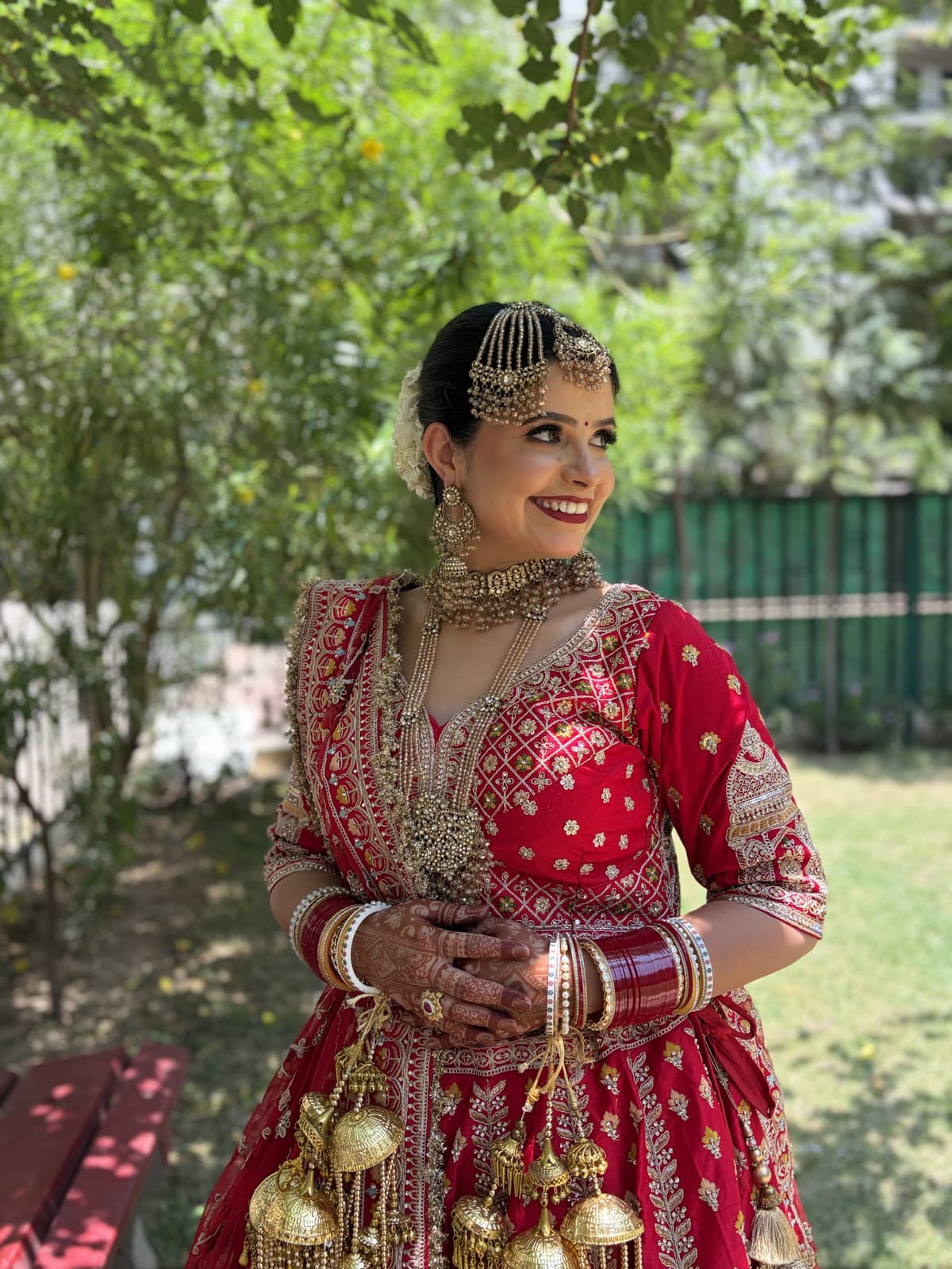 Rimple in red bridal attire with luminous makeup and traditional jewellery