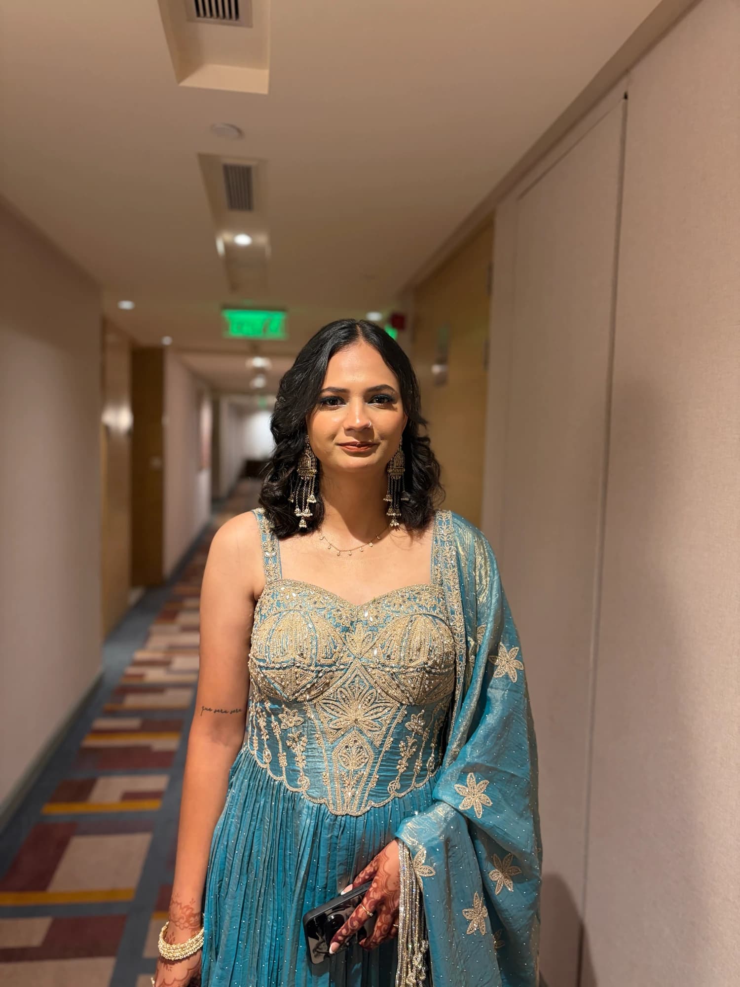 Party portrait with softly glowing skin and curled hair, wearing a teal and gold embroidered outfit