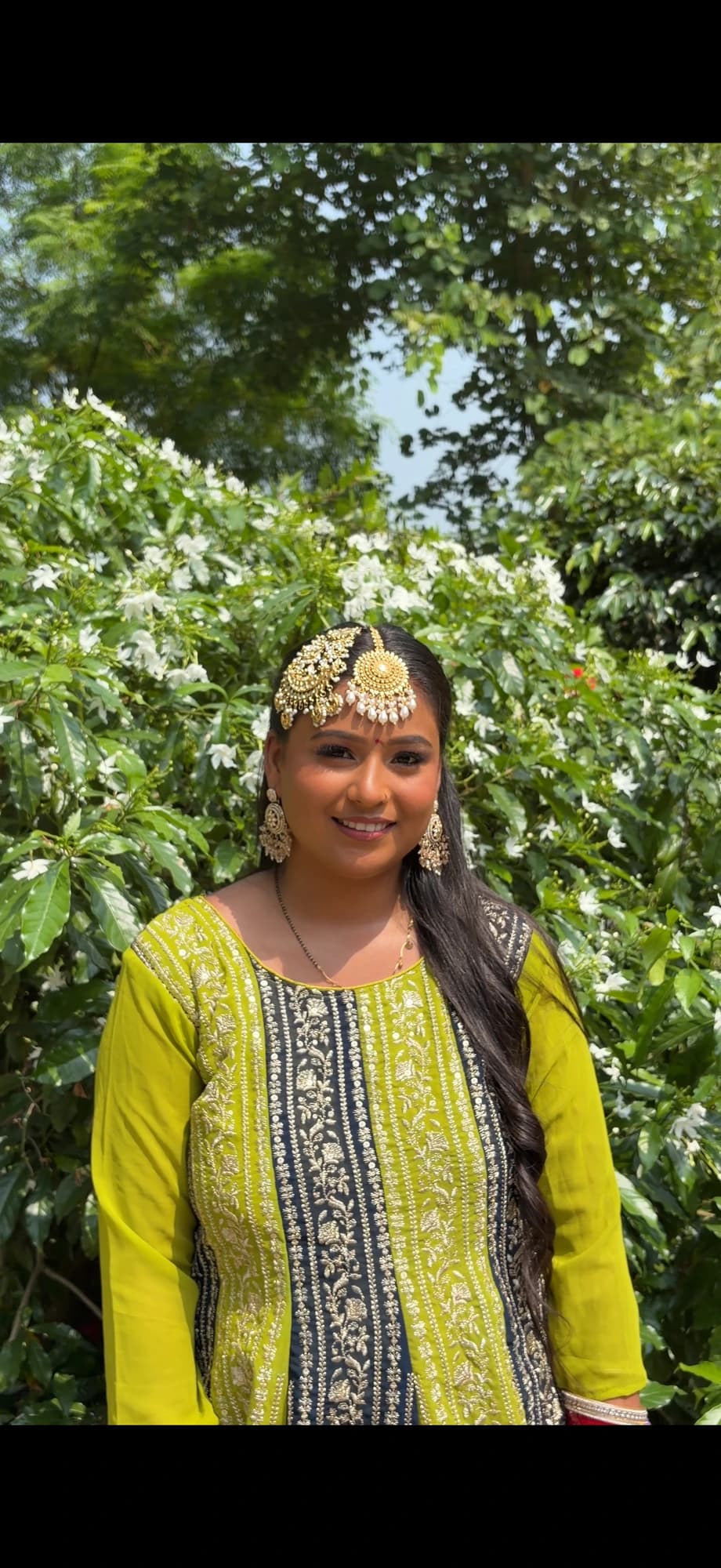 Outdoor mehndi look with glowing skin, gold forehead jewellery and a lime green embroidered outfit
