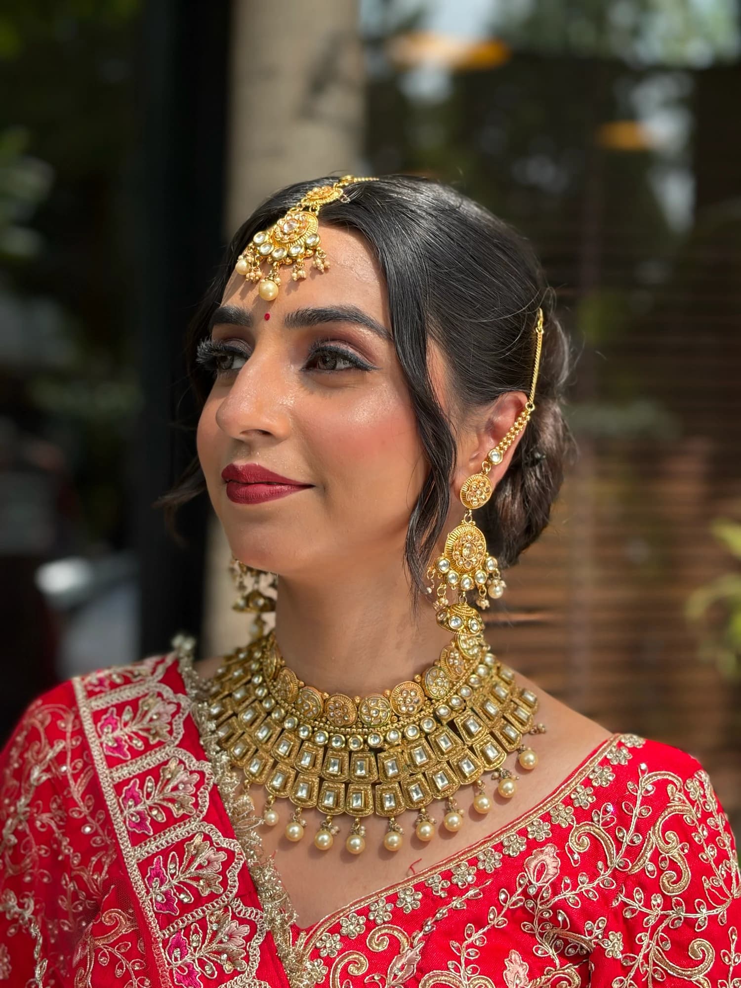 Bridal makeup close-up showing warm eye shadow, softly blushed cheeks, rose lips and gold jewellery